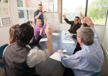 Business meeting at a table raising hands