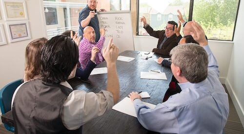 Business meeting at a table raising hands